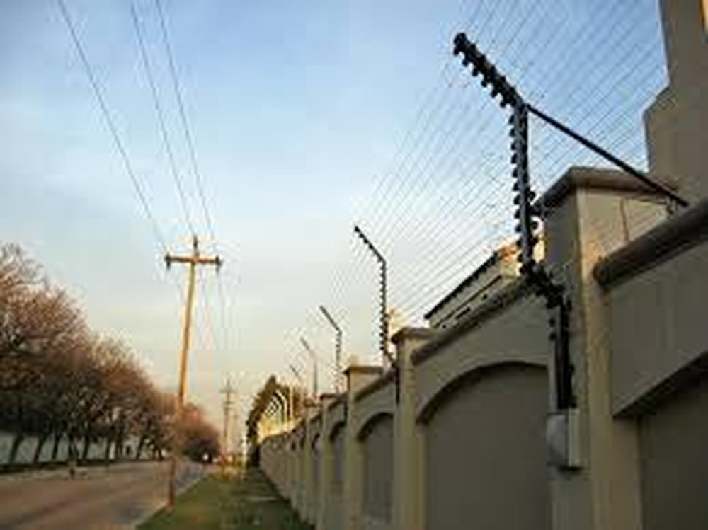 Wall-top electric security fencing along a property perimeter